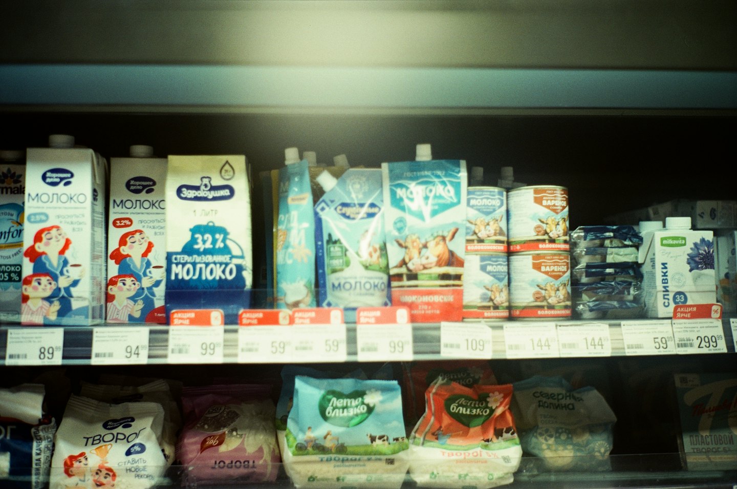 Refrigerated shelf stocked with milk, cream, and cottage cheese.