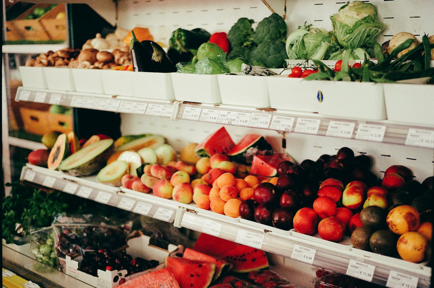 Colorful fruits and vegetables neatly arranged on grocery store shelves.